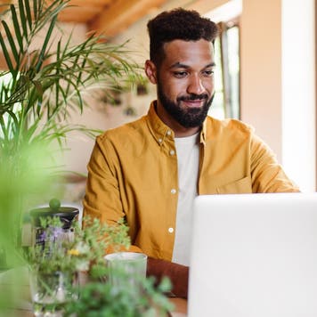 Young man with laptop and coffee working indoors